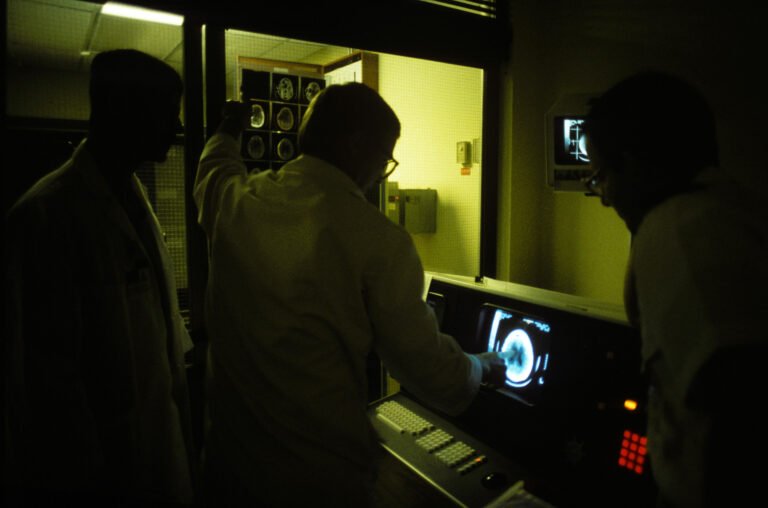 A clinical team discusses a scan displayed on a monitor during a care-planning discussion