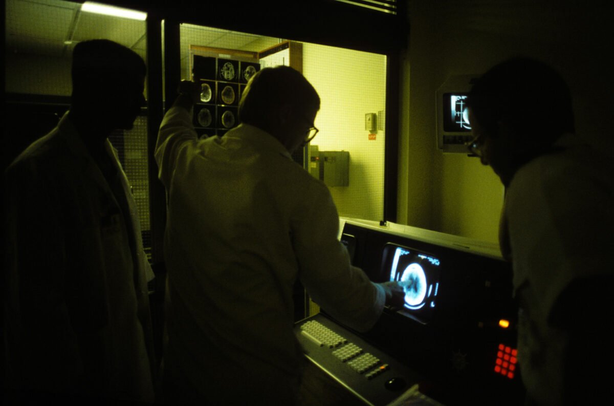 A clinical team discusses a scan displayed on a monitor during a care-planning discussion