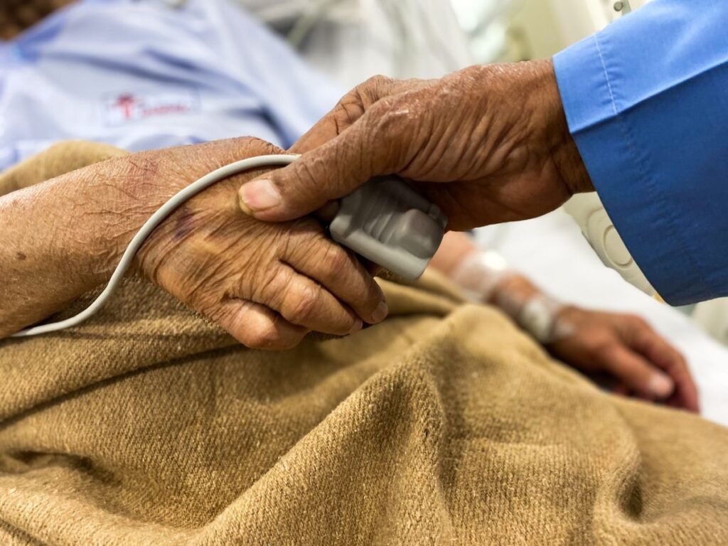 A supportive hand comforting a patient in a hospital setting, representing patient and caregiver support